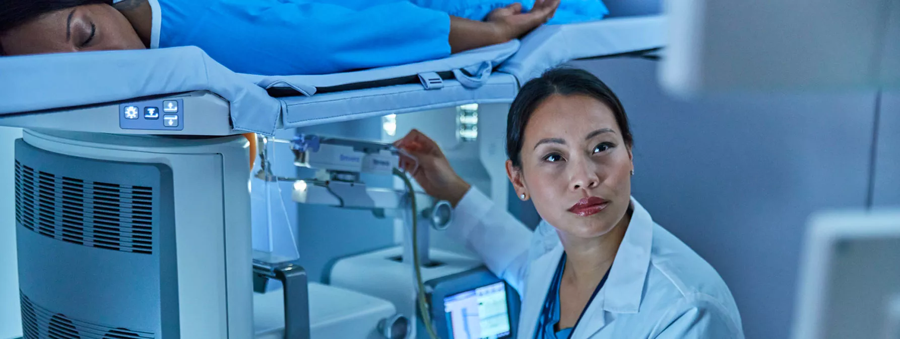 Woman lying down on breast imaging system with technician