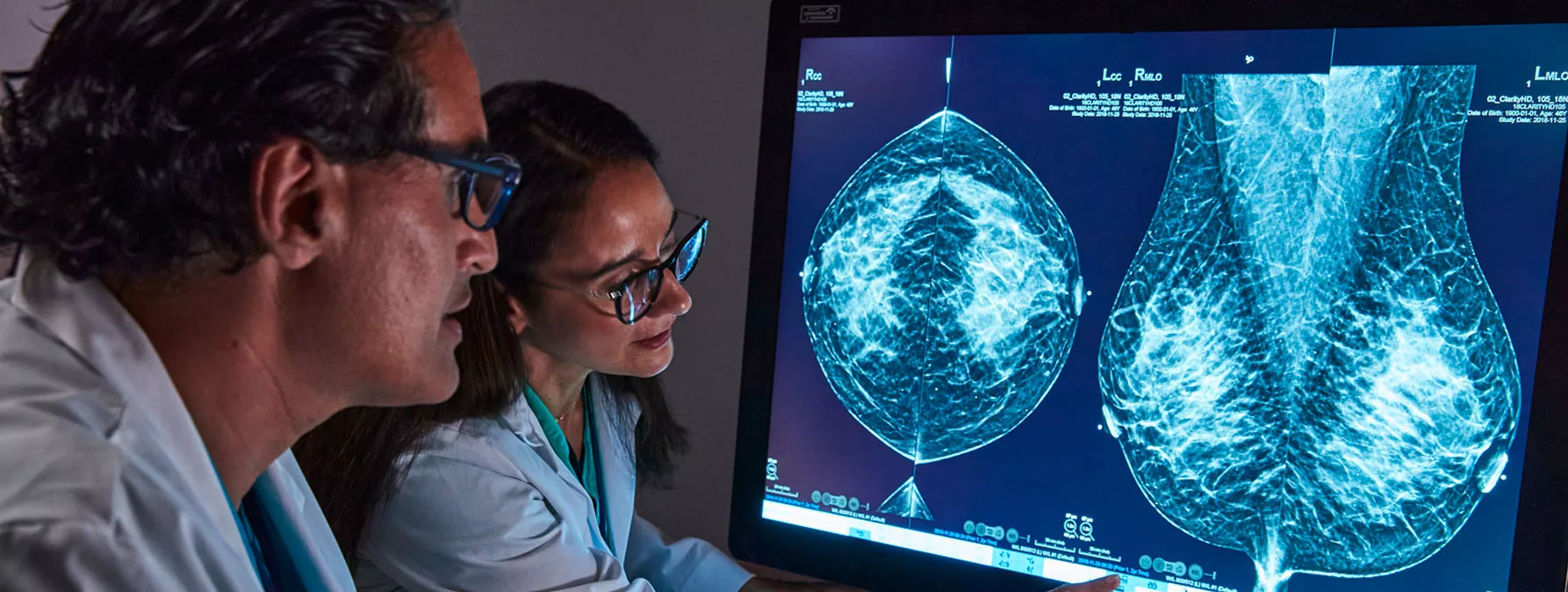 Healthcare professional pointing to breast scan image on monitor