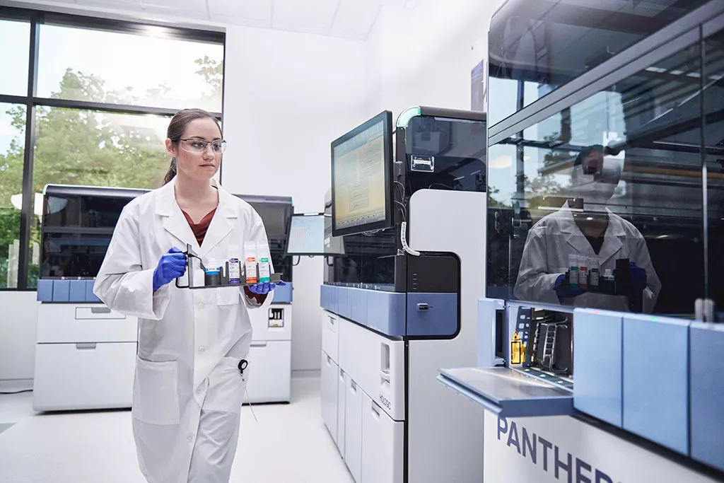Tecnico di laboratorio con un vassoio di campioni da inserire nel sistema Panther